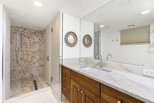 bathroom with vanity, a tile shower, and tile patterned floors