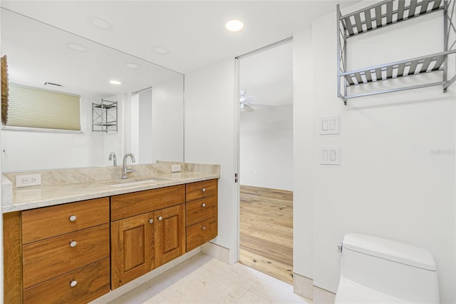 bathroom with vanity, toilet, hardwood / wood-style flooring, and ceiling fan