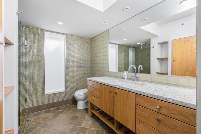 bathroom featuring a skylight, an enclosed shower, toilet, vanity, and tile patterned flooring