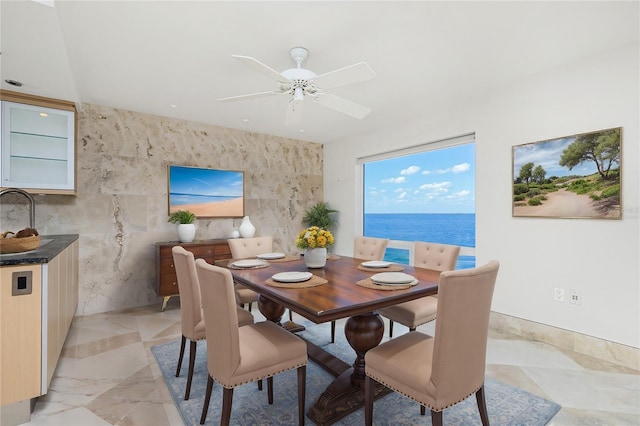 dining room featuring marble finish floor, a water view, and ceiling fan