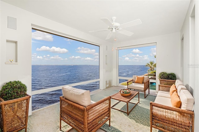 sunroom with a ceiling fan and a water view