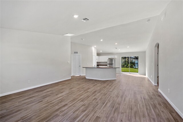 unfurnished living room featuring vaulted ceiling and hardwood / wood-style flooring