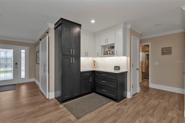 kitchen with a barn door, white cabinetry, and light hardwood / wood-style flooring