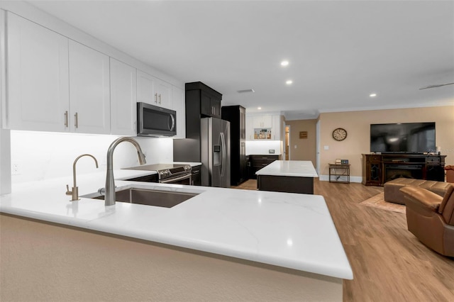 kitchen featuring sink, a center island, kitchen peninsula, light hardwood / wood-style floors, and appliances with stainless steel finishes