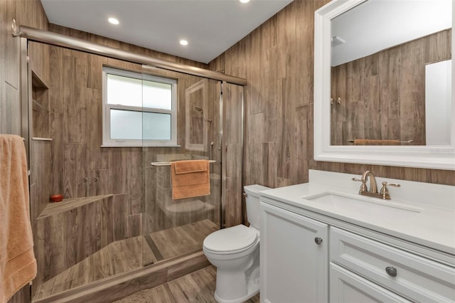 bathroom with vanity, wood walls, toilet, walk in shower, and wood-type flooring