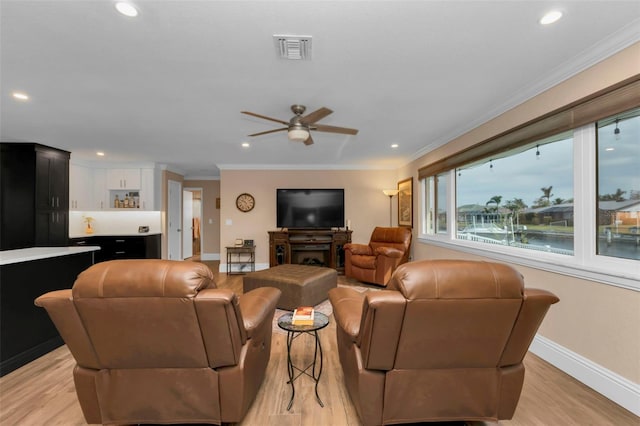 living room with ceiling fan, a fireplace, crown molding, and light hardwood / wood-style flooring