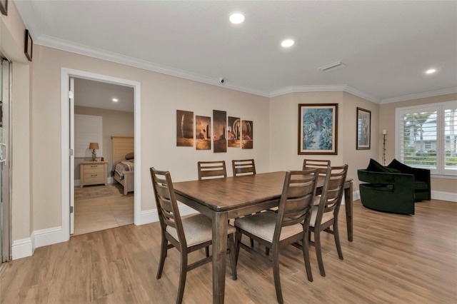 dining space with crown molding and light hardwood / wood-style flooring