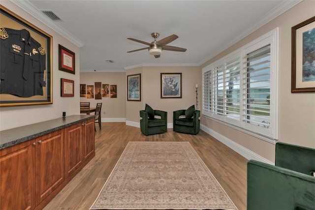 sitting room featuring visible vents, ornamental molding, wood finished floors, baseboards, and a ceiling fan