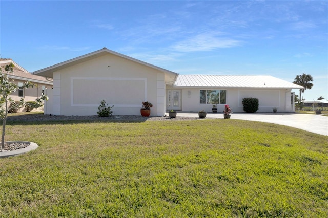 ranch-style home with a front yard, metal roof, driveway, and stucco siding