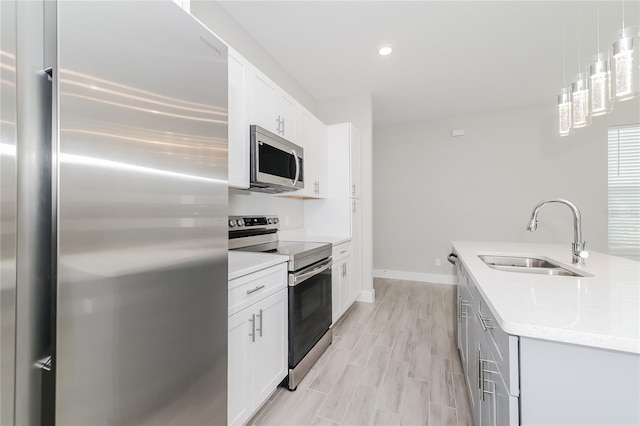 kitchen featuring appliances with stainless steel finishes, white cabinetry, light stone countertops, sink, and decorative light fixtures