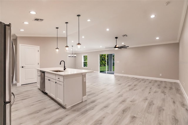 kitchen featuring sink, stainless steel appliances, white cabinets, a center island with sink, and decorative light fixtures