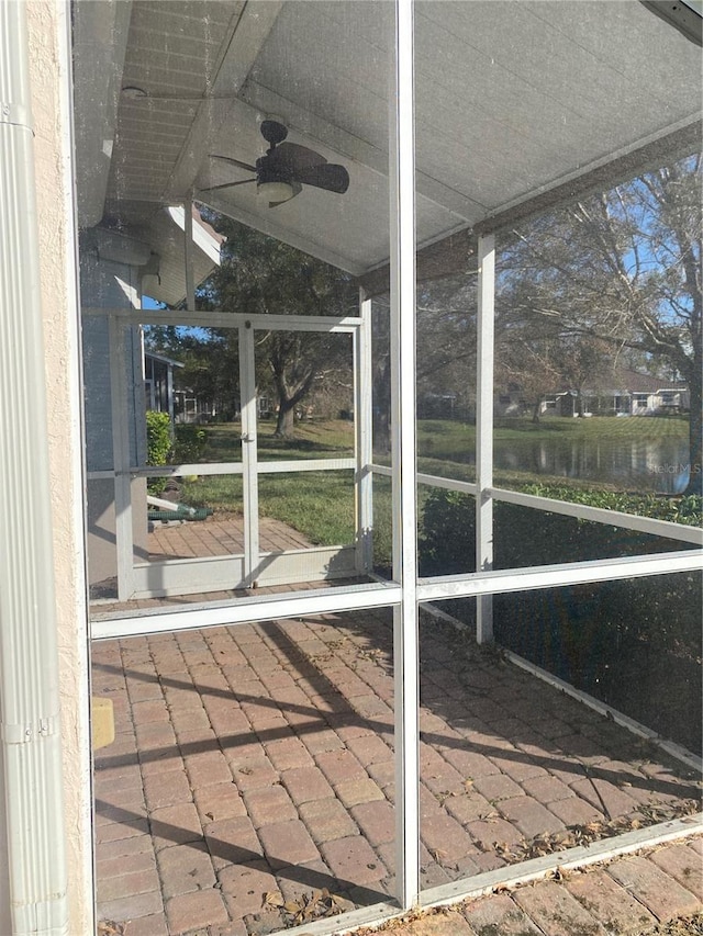 unfurnished sunroom with ceiling fan, a water view, and lofted ceiling