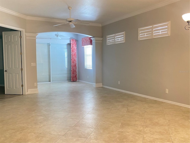 empty room featuring light tile patterned floors, ornate columns, ceiling fan, and crown molding