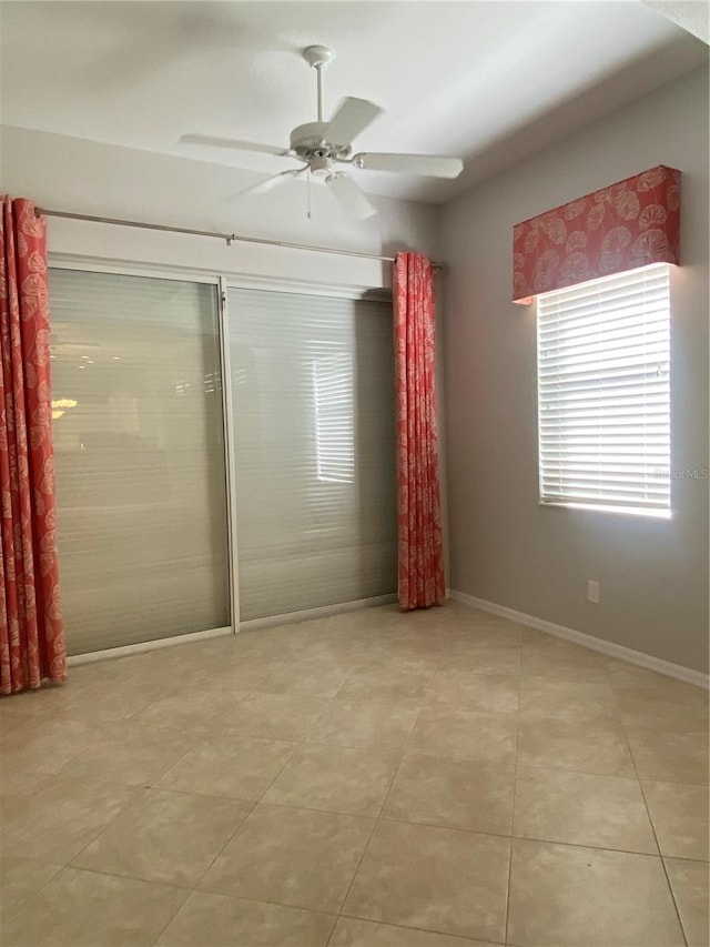 tiled spare room with ceiling fan