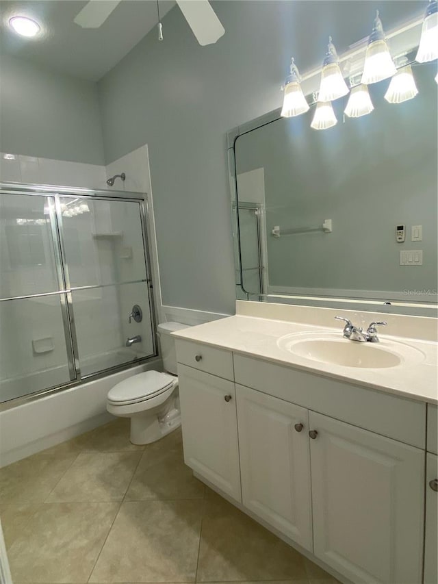 full bathroom with vanity, tile patterned floors, combined bath / shower with glass door, ceiling fan, and toilet