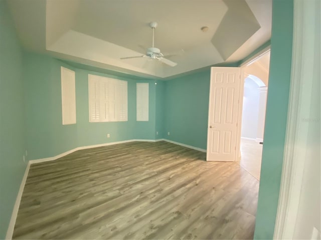 unfurnished bedroom with a raised ceiling, ceiling fan, and hardwood / wood-style floors