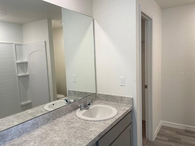 bathroom featuring vanity, toilet, wood-type flooring, and walk in shower