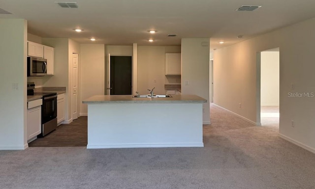 kitchen with white cabinets, stainless steel appliances, light colored carpet, and a kitchen island with sink