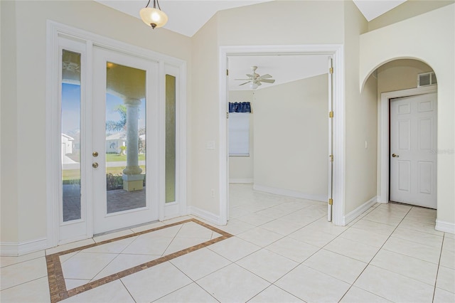 doorway with ceiling fan, light tile patterned floors, and vaulted ceiling