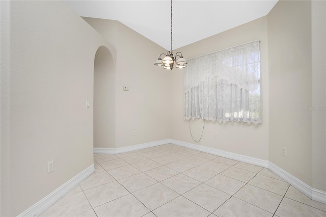 tiled empty room with vaulted ceiling and a notable chandelier