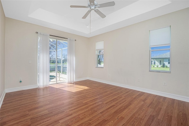 spare room featuring ceiling fan, wood-type flooring, and a raised ceiling