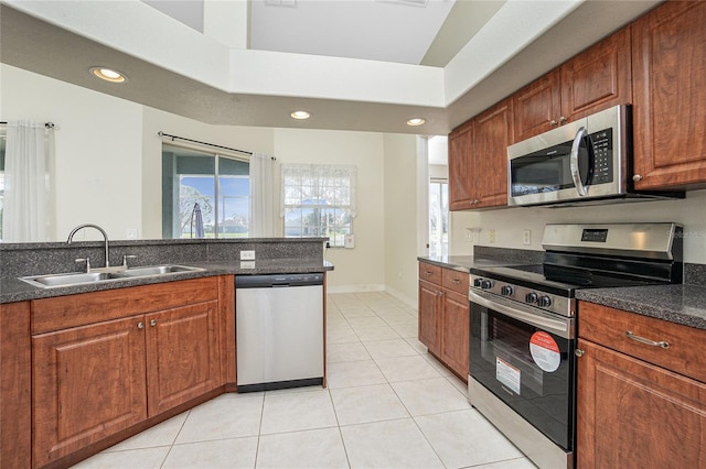 kitchen featuring stainless steel appliances, dark stone countertops, light tile patterned floors, and sink