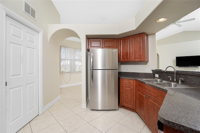 kitchen with lofted ceiling, sink, stainless steel refrigerator, and light tile patterned floors