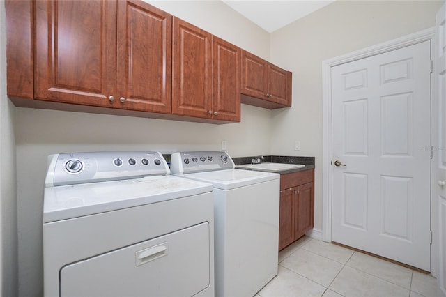 washroom featuring independent washer and dryer, cabinets, sink, and light tile patterned floors