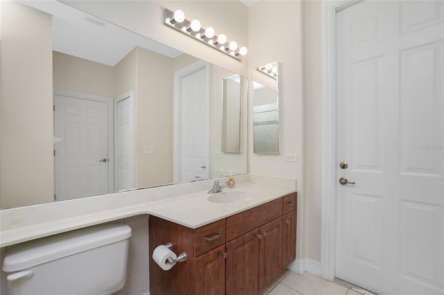 bathroom with toilet, vanity, and tile patterned floors