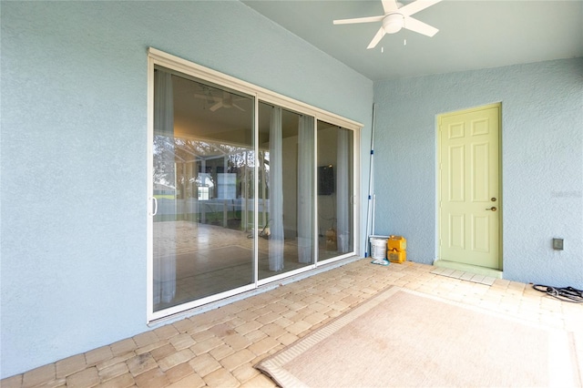 entrance to property with ceiling fan and a patio area