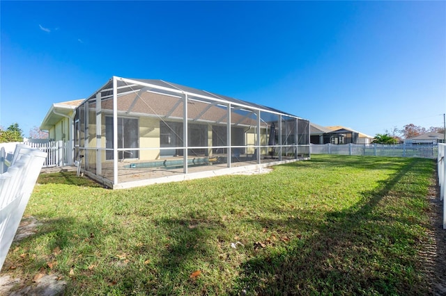 rear view of house with a lawn, a lanai, and a fenced in pool