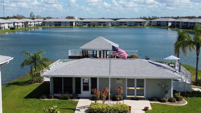 exterior space featuring a sunroom, a water view, and a front lawn