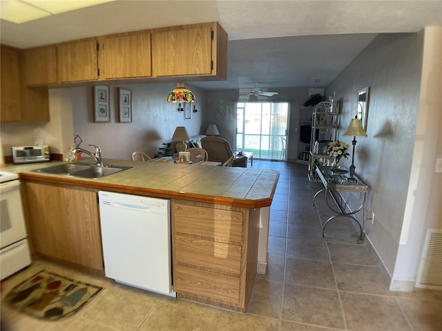 kitchen featuring sink, kitchen peninsula, ceiling fan, white appliances, and tile counters