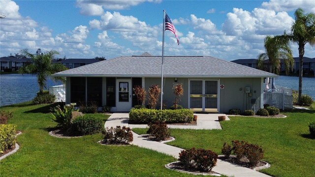 3310 Loveland Blvd Unit 604, Port Charlotte, FL 33980 - rear view of property with a yard, a shingled roof, and a water view