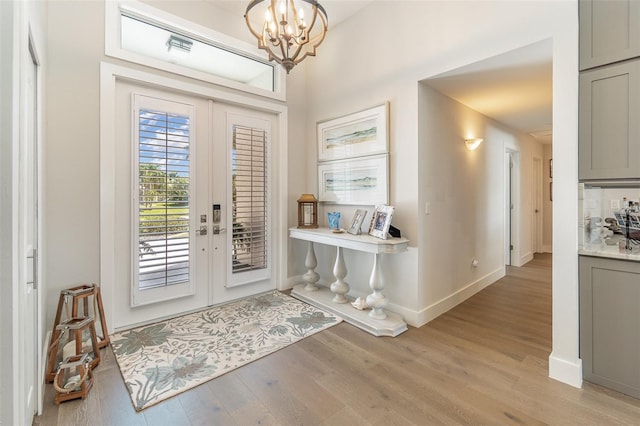 foyer featuring light hardwood / wood-style floors, french doors, and a notable chandelier