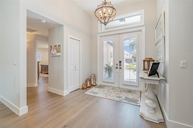 foyer entrance with french doors, a notable chandelier, and light hardwood / wood-style flooring