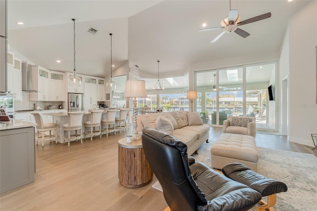 living room with light hardwood / wood-style floors, high vaulted ceiling, and ceiling fan