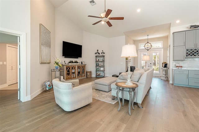 living room featuring a high ceiling, light hardwood / wood-style floors, and ceiling fan