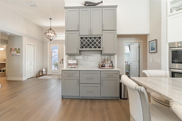 kitchen featuring gray cabinetry, light hardwood / wood-style floors, and hanging light fixtures