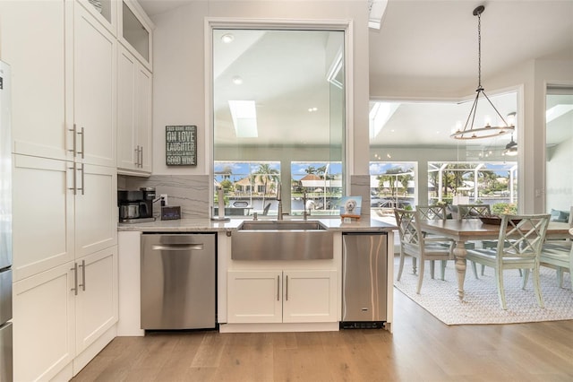 kitchen with white cabinetry, light hardwood / wood-style floors, decorative light fixtures, and stainless steel dishwasher