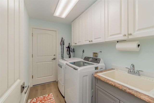 laundry area featuring sink, light hardwood / wood-style flooring, separate washer and dryer, and cabinets