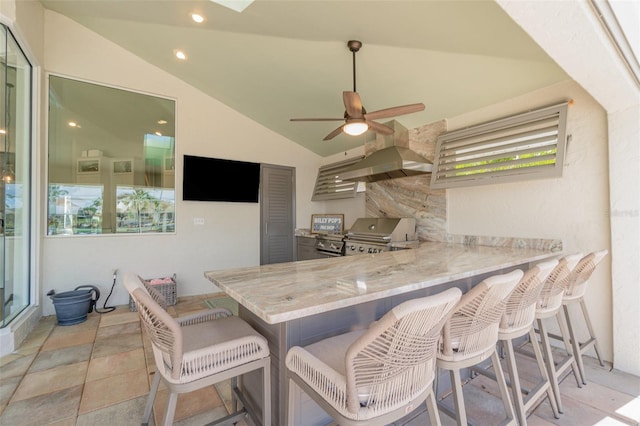 kitchen featuring light stone counters, a kitchen breakfast bar, vaulted ceiling, and kitchen peninsula