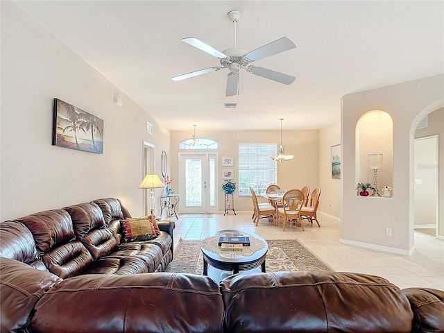 tiled living room with ceiling fan with notable chandelier