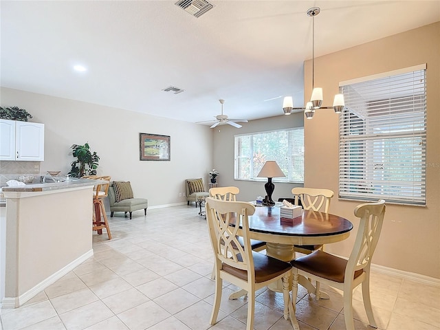 tiled dining room featuring ceiling fan with notable chandelier