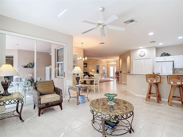 tiled living room featuring ceiling fan with notable chandelier