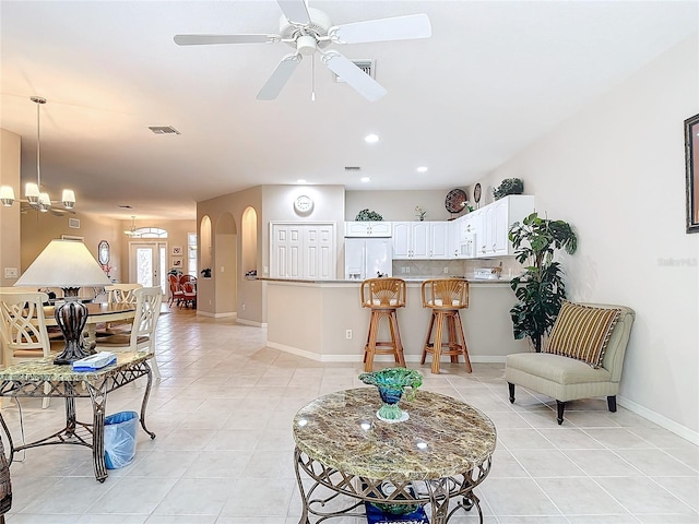 tiled living room featuring ceiling fan with notable chandelier