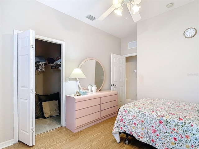 bedroom featuring light hardwood / wood-style flooring, a closet, a spacious closet, and ceiling fan