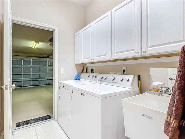 clothes washing area featuring cabinets, sink, washing machine and clothes dryer, and light tile patterned floors