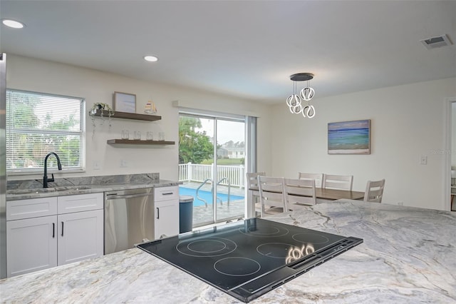 25 Caddy Rd, Rotonda West, FL 33947 - kitchen with stainless steel dishwasher, a sink, white cabinets, light stone countertops, and hanging light fixtures