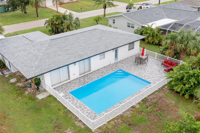 view of swimming pool featuring a patio area, a lawn, and glass enclosure